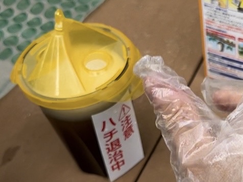 アースの蜂捕獲器。誘引液と水を入れた容器に黄色いフタをしっかり閉める様子