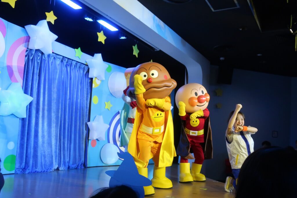 神戸アンパンマンこどもミュージアムのショーステージ。アンパンマンとカレーパンマン、お姉さんが踊っている様子を最前列近くから撮影