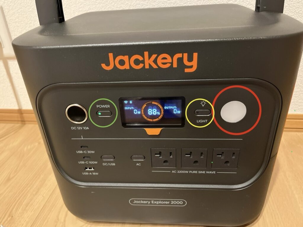 Jackery 2000 Newの正面パネルのLEDライト解説図。中央の液晶画面を挟んで、左側にメイン電源ボタン、右側にLEDライトのスイッチと光源。