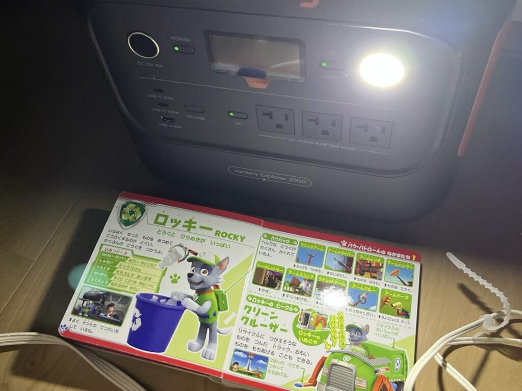 Jackeryポータブル電源のLEDライトを光源にして絵本を広げた写真