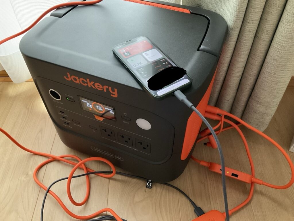 SolarSaga 100の多機能アダプタにあるUSBポートからスマートフォンを直接充電している様子。スマホのディスプレイには充電量94%と表示されている。