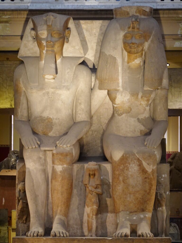 カイロのエジプト博物館に展示されているアメンヘテプ3世と王妃ティイの巨大な座像。足元には3人の娘が刻まれ、古代エジプト第18王朝の家族像として知られる。