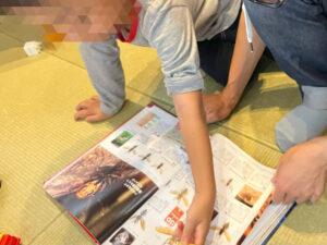 親子で危険生物図鑑を開き、スズメバチの特徴を真剣に見ています。学びながら自然への理解を深めるひととき。